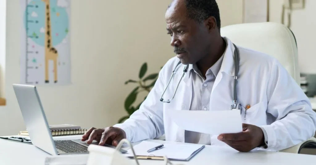 Doctor reviewing patient records on a computer, performing a CDI query to ensure accurate and compliant clinical documentation.