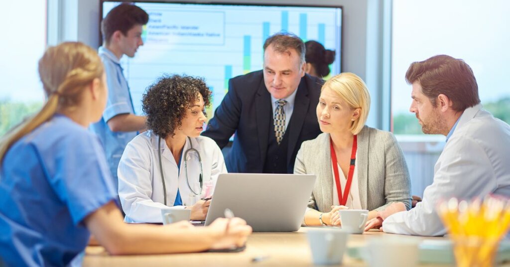 Image of a doctor, a nurse, and hospital staff gathered around a laptop