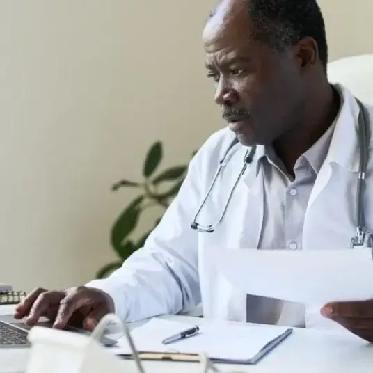 Doctor reviewing patient records on a computer, performing a CDI query to ensure accurate and compliant clinical documentation.